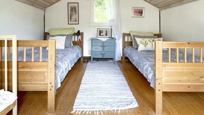 A cozy attic bedroom with two wooden beds, a dresser, and a window with curtains. - 4 Person Holiday Home in Kolmarden (Kolmården)