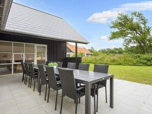 An outdoor patio with a table and chairs, a potted plant, and a view of a house with a sloped roof. - 14 Person Holiday Park Home in Blavand (Blavand)