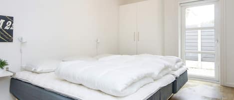 Un dormitorio con cama, armario, puerta y una lámpara fijada a la pared.