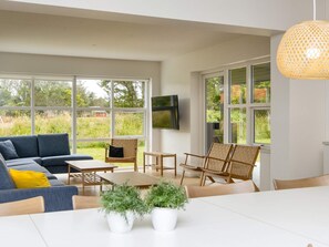 A spacious living area with a sofa, chairs, a coffee table, and a TV mounted on the wall. - 14 Person Holiday Park Home in Blavand (Blavand)