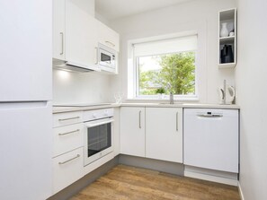 A modern kitchen with white cabinetry, a built-in oven, a microwave, and a dishwasher. - 14 Person Holiday Park Home in Blavand (Blavand)