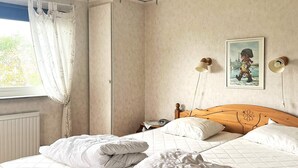 A bedroom with two beds, a nightstand, a lamp, and a painting on the wall. - 6 Person Holiday Home in Skummeslovsstrand (Skummesloevsstrand)