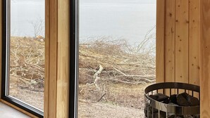 Ein Zimmer mit großem Fenster mit Blick auf ein Gewässer und eine felsige Landschaft.