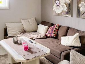 A living room with a brown sofa, a coffee table, and a painting on the wall. - 10 Person Holiday Home in Skummeslovsstrand (Skummesloevsstrand)