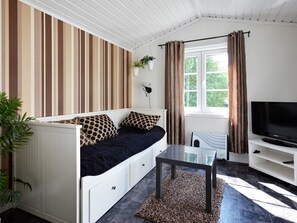 Une chambre avec un lit, une télévision, une table et une fenêtre avec des rideaux.