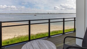 A view from a balcony overlooking a beach with a sandy shore and a body of water. - Seaside Escape, Sint-annaland (Sint-Annaland)