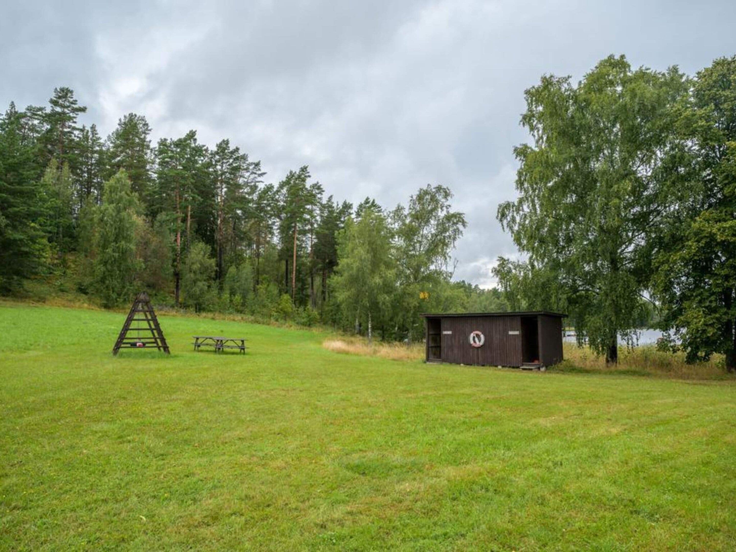 Un campo cubierto de hierba con una mesa de picnic y un cobertizo pequeño.