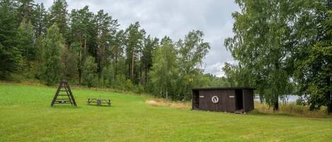 A grassy field with a picnic table and a small shed.