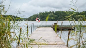 A wooden pier leading to a dock with a lifebuoy and a metal railing. - 4 Star Holiday Home in Sparreholm (Sparreholm)
