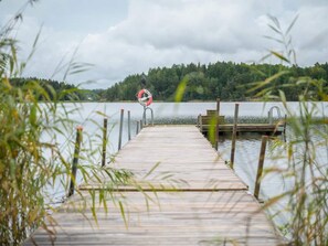 A wooden pier leading to a dock with a lifebuoy and a metal railing. - 4 Star Holiday Home in Sparreholm (Sparreholm)