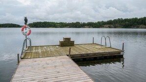 A wooden dock extending into calm water with a lifebuoy attached to a metal railing. - 4 Star Holiday Home in Sparreholm (Sparreholm)