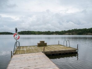 A wooden dock extending into calm water with a lifebuoy attached to a metal railing. - 4 Star Holiday Home in Sparreholm (Sparreholm)