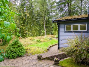 A house with a paved driveway leading to a wooden deck, surrounded by a forested area. - 4 Star Holiday Home in Sparreholm (Sparreholm)