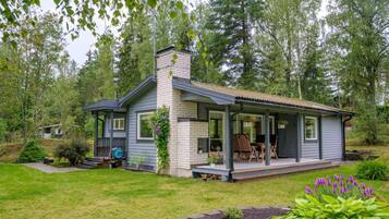 A single-story house with a porch, a chimney, and a small deck area.