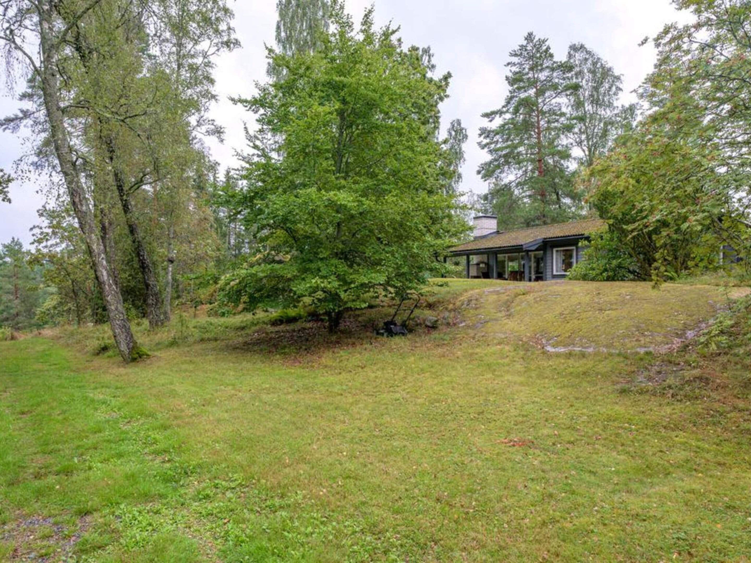 A house with a covered porch, surrounded by a grassy area and trees.
