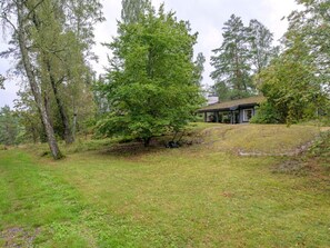 A house with a covered porch, surrounded by a grassy area and trees. - 4 Star Holiday Home in Sparreholm (Sparreholm)