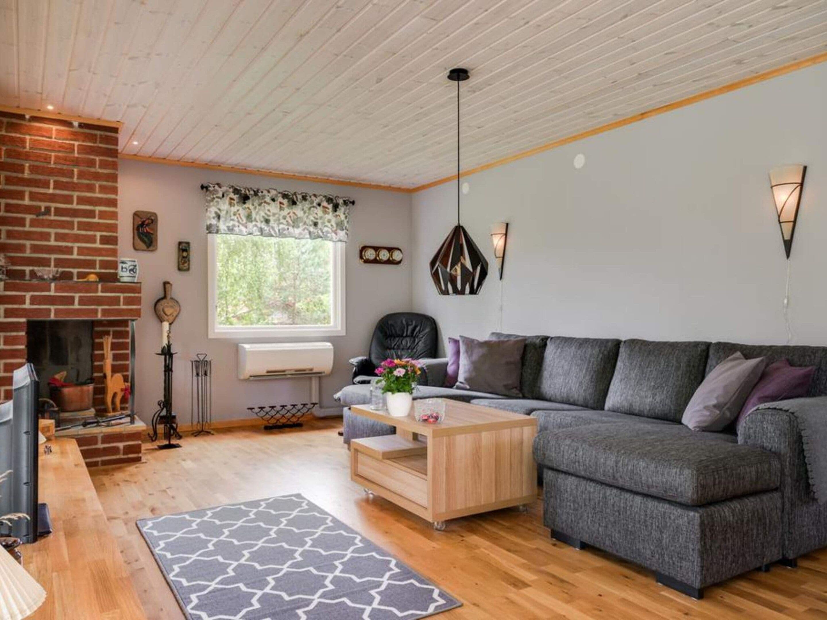 A cozy living room with a fireplace, a sofa, a coffee table, and a patterned rug.
