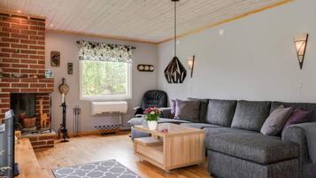 A cozy living room with a fireplace, a sofa, a coffee table, and a patterned rug.