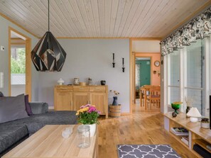 Een moderne woonkamer met een houten plafond, een bank, een salontafel en een eethoek met een tafel en stoelen.