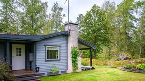 A single-story house with a front porch, a brick chimney, and a well-maintained lawn. - 4 Star Holiday Home in Sparreholm (Sparreholm)