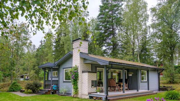 A single-story house with a porch, a chimney, and a garden with plants and a lawn. - 4 Star Holiday Home in Sparreholm (Sparreholm)