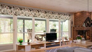 Una sala de estar moderna con televisor, estanterías, chimenea y ventanas amplias.