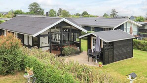 Een modern huis met een ruim terras, een eettafel en een kleine tuin.
