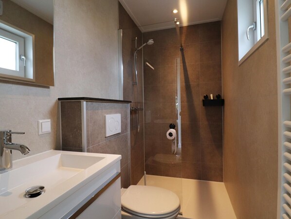 A modern bathroom with a shower, toilet, and sink.