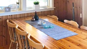 Een houten eettafel met een grijze placemat, omringd door zes houten stoelen.