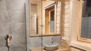 A bathroom with a wooden vanity, a glass-enclosed shower, and a large mirror. - Alpine hut in Rauris ski Hiking Area With Sauna (Rauris)