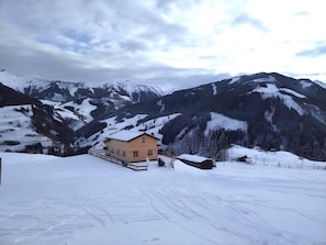 A snow-covered mountain landscape with a single yellow building in the foreground. - Alpine hut in Rauris ski Hiking Area With Sauna (Rauris)