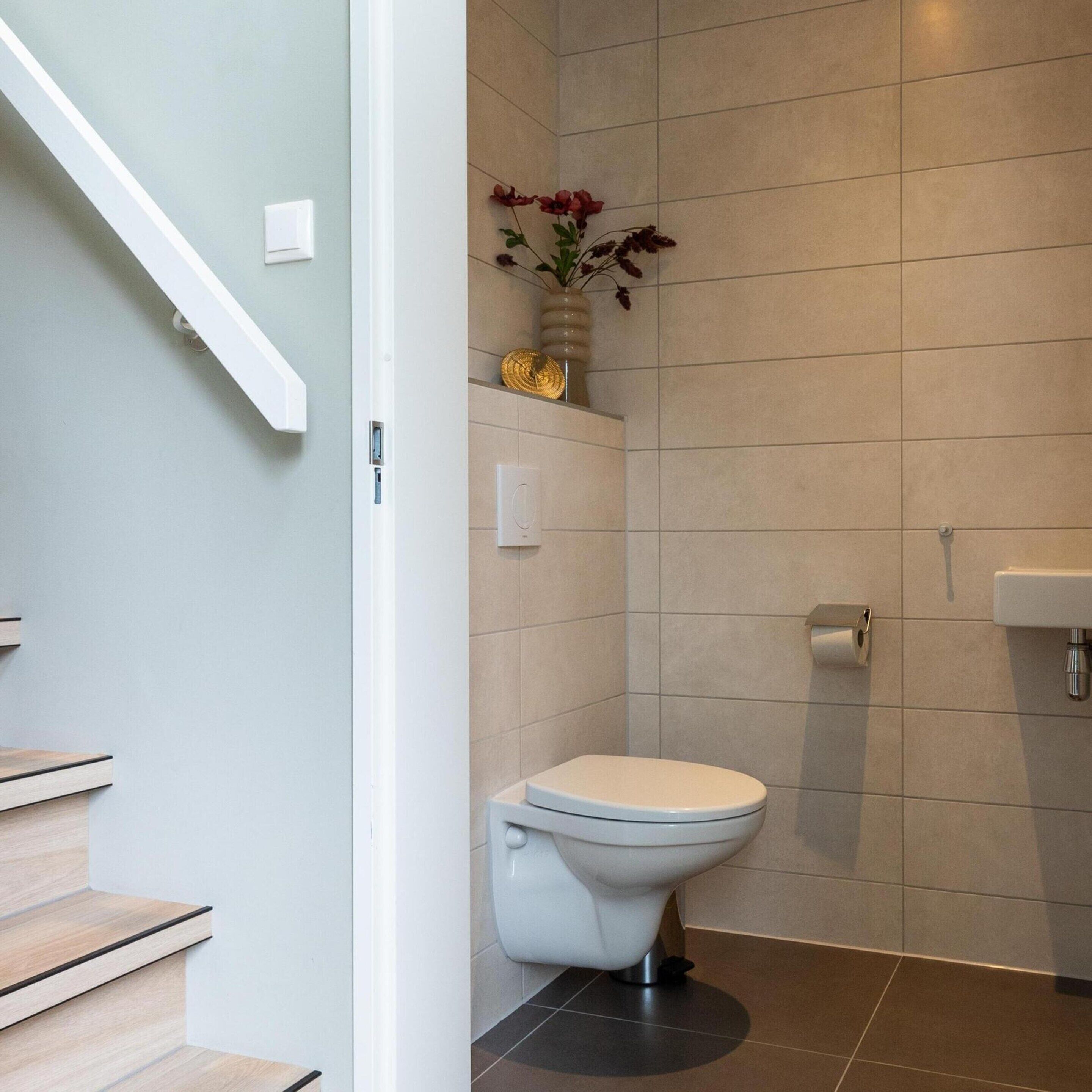 Un baño moderno con inodoro, lavamanos y zona de ducha.