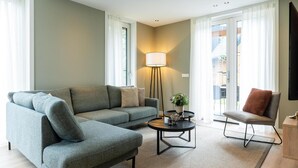 Ein modernes Wohnzimmer mit einem grauen Sofa, einem kleinen runden Couchtisch und einer Stehlampe.