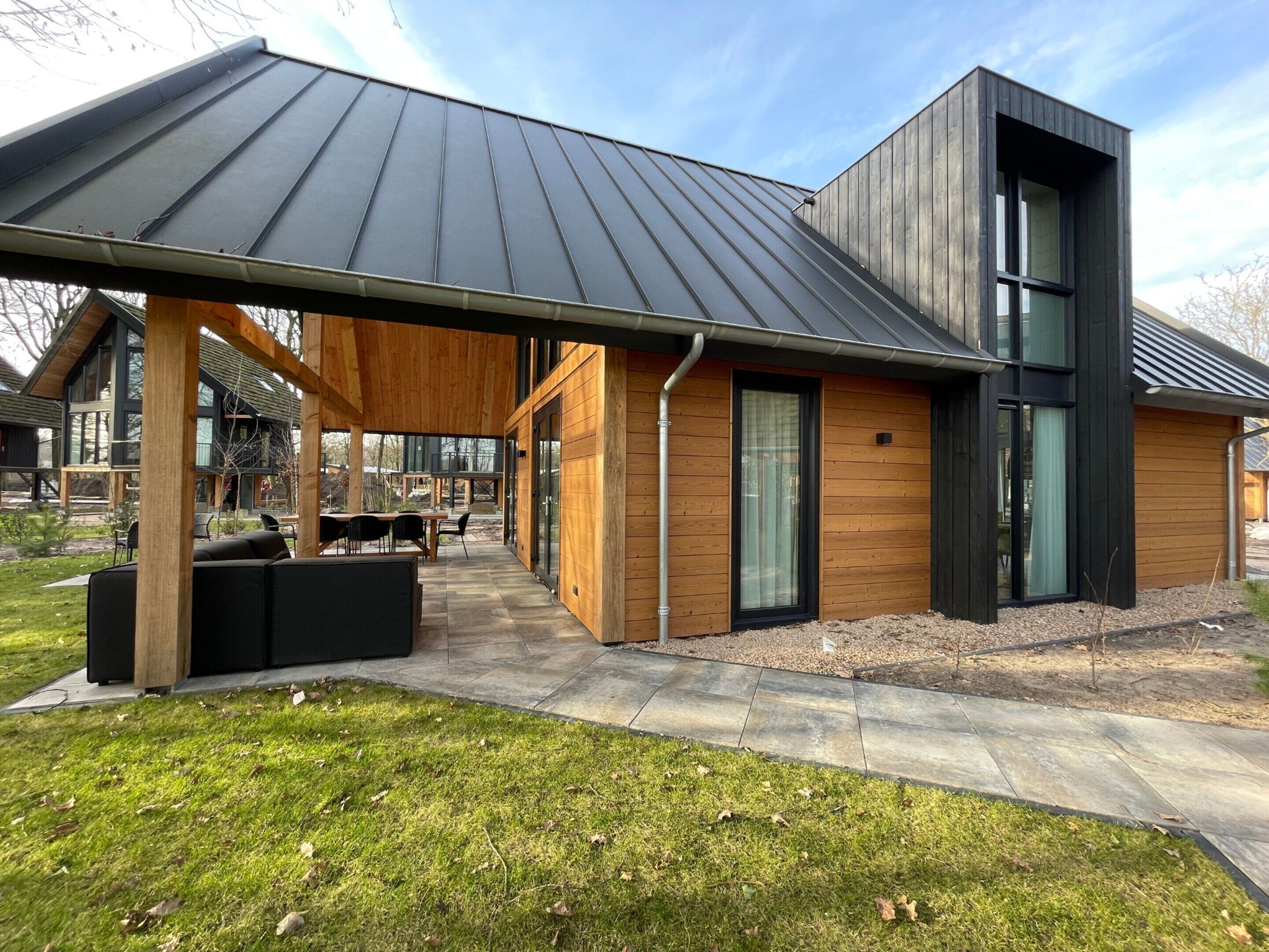 A modern house with a covered patio, a large window, and a stone pathway.