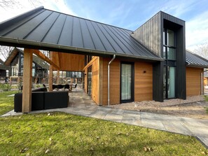 A modern house with a covered patio, a large window, and a stone pathway. - Forest Villa 6 Persons (Wekerom)