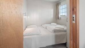 A small, single-bed room with white walls and a wooden door.