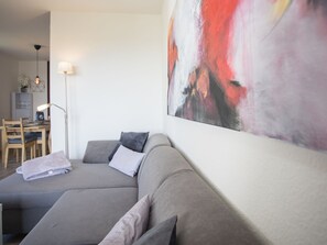 Relax in this stylish living room with a sofa, dining area, and abstract art piece.