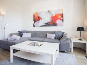 Relax in this stylish living room with a grey sofa, coffee table, and side table, featuring a beautiful abstract painting.