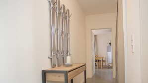 A hallway with a wooden console table, a wall-mounted sculpture, and a glimpse of a dining area in the background. - Gemutliches Apartment in Winterberg mit Balkon (Winterberg)