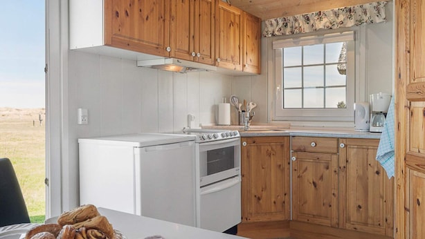 Una cocina con armarios de madera, una estufa blanca y una ventana con vistas al exterior.