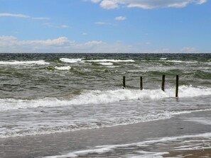A beach with waves crashing onto the shore and a clear sky.