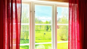 A room with a large window, red curtains, and a view of a green landscape. - 4 Star Holiday Home in Bralanda (Bralanda)
