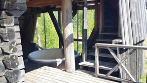 A rustic wooden cabin with a hot tub and a wooden staircase leading to an upper level. - 7 Person Holiday Home in Saffle (Saffle)