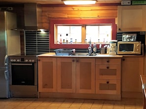 A compact kitchen with wooden cabinets, a built-in oven, a sink, and a microwave.