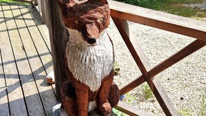 A wooden sculpture of a dog on a wooden deck.