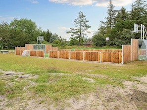 Un terrain de sport clôturé, avec des poteaux de but et une clôture en bois.