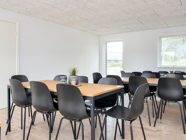 Ett konferensrum med flera bord och stolar, en krukväxt och ett stort fönster som släpper in naturligt ljus.