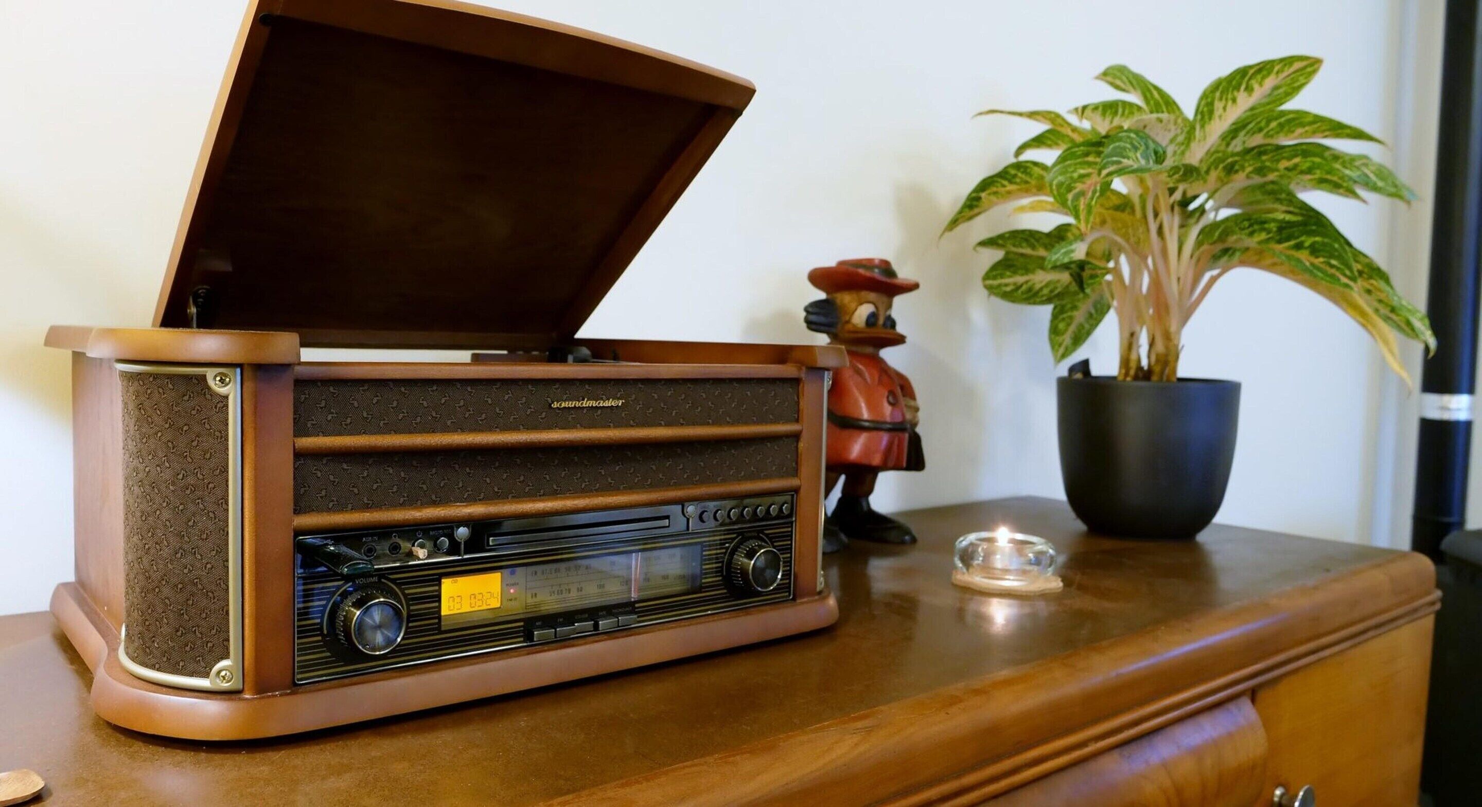 A vintage radio on a wooden cabinet with a plant and a figurine beside it.