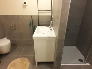 Een badkamer met toilet, wastafel en douche.