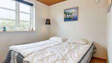 A bedroom with a bed, a window, a painting, and a radiator.